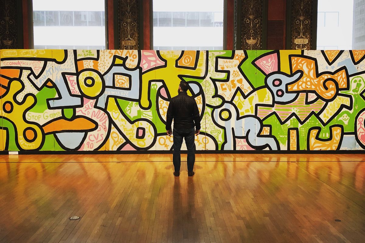 A man looking at a Keith Haring piece at an art gallery