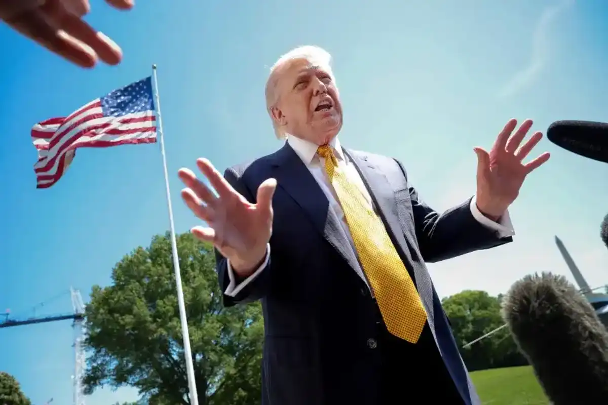 President Donald Trump speaks in front of the American flag to the press as he departs the White House on May 12, 2026, in Washington, D.C.