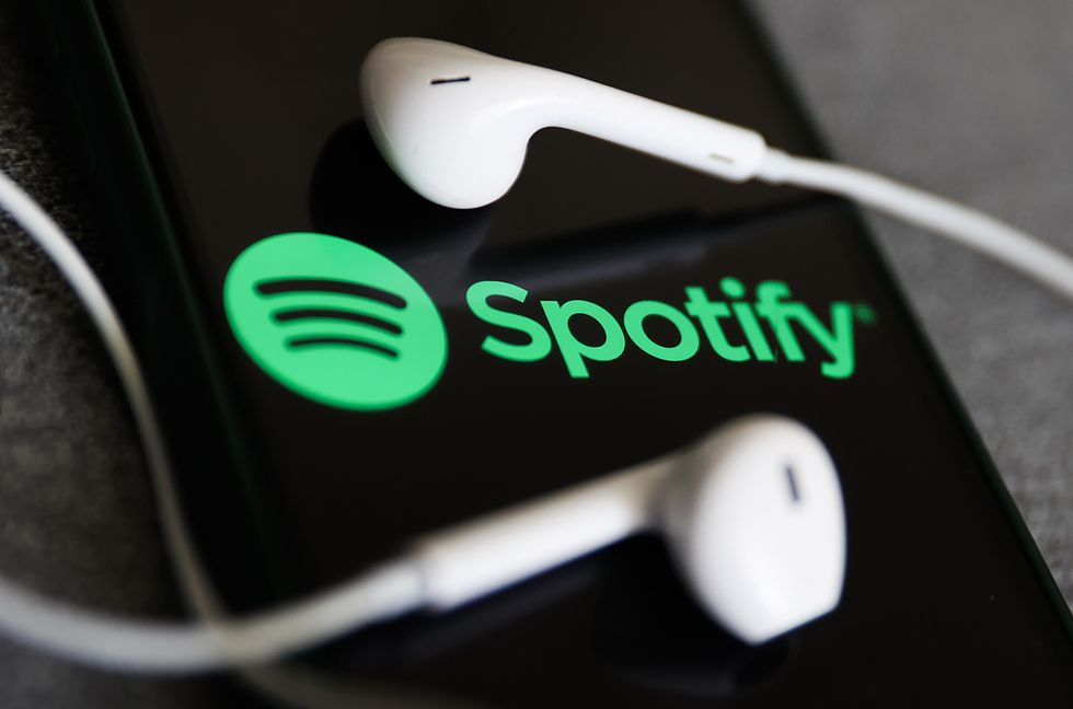 Spotify logo displayed on a phone screen and headphones are seen in this illustration photo taken in Krakow, Poland on July 12, 2022.